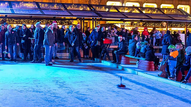 Menschen spielen Eisstockschießen auf dem Eis.
