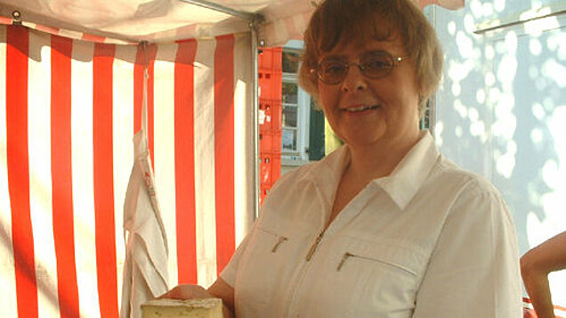 Frau hält Käse in die Kamera