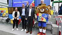 Menschen stehen mit dem UEFA EURO Maskottchen zusammen