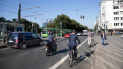 Menschen auf Fahrrädern, zu Fuß und eine Bahn