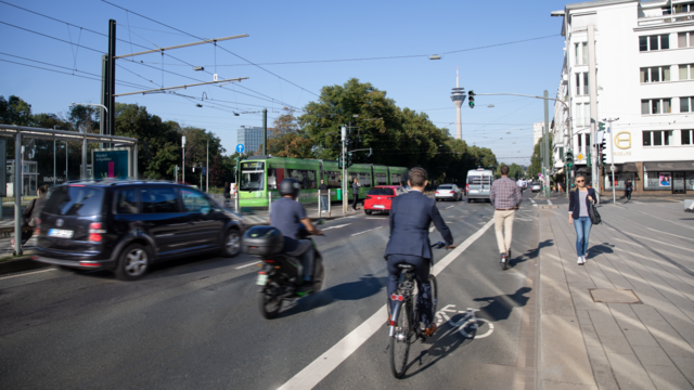 Menschen auf Fahrrädern, zu Fuß und eine Bahn