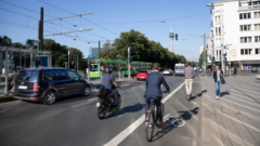 Menschen auf Fahrrädern, zu Fuß und eine Bahn