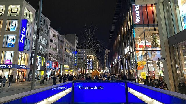 Die Schadowstraße mit dem Eingang zur U-Bahn und den Hütten im Hintergrund.