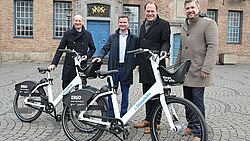 Männer stehen hinter zwei Fahrrädern.