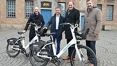 Männer stehen hinter zwei Fahrrädern.