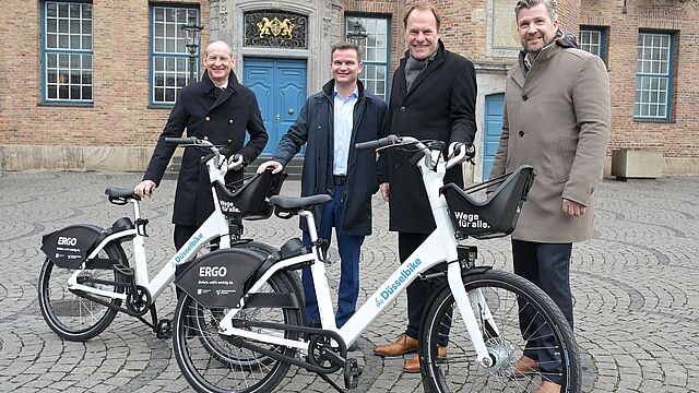 Männer stehen hinter zwei Fahrrädern.