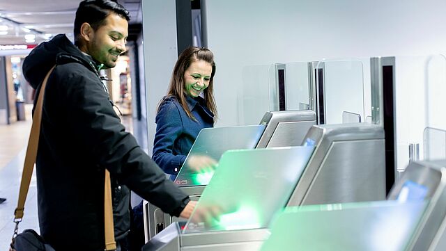 Zwei Menschen an einem Scan Automaten am Flughafen.