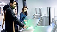 Zwei Menschen an einem Scan Automaten am Flughafen.