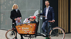 Personen stehen neben einem Lastenfahrrad, zwei Kinder sitzen drin