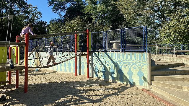Kinder klettern über ein Spielgerüst.