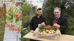 Zwei Männer halten Äpfel in den Händen