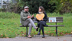 Zwei Menschen sitzen auf einer Parkbank