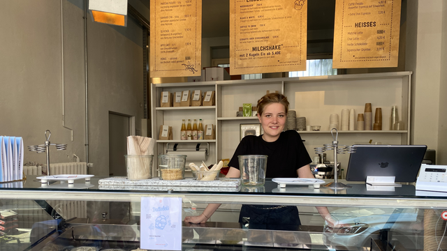 Frau steht hinter der Eis-Theke