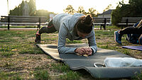 Frau macht eine Plank auf einer Matte im Freien