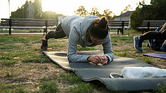 Frau macht eine Plank auf einer Matte im Freien