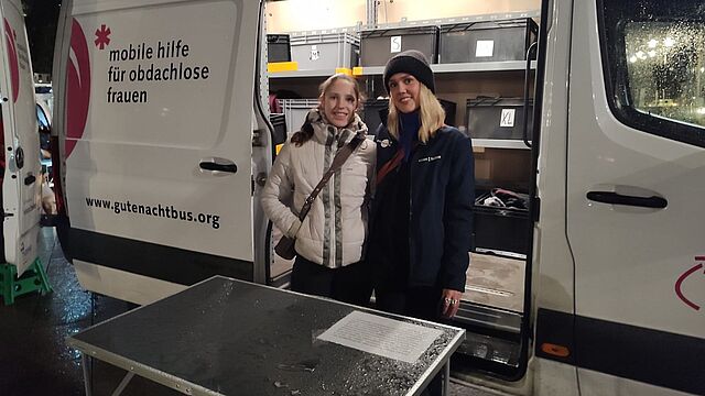 Zwei Frauen stehen vor einem Bus.