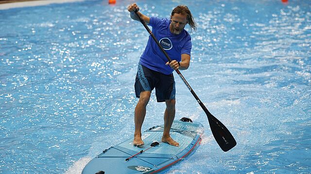 Mann surft mit Paddel