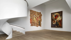 Ein Raum mit Gemälden und geschwungener Treppe